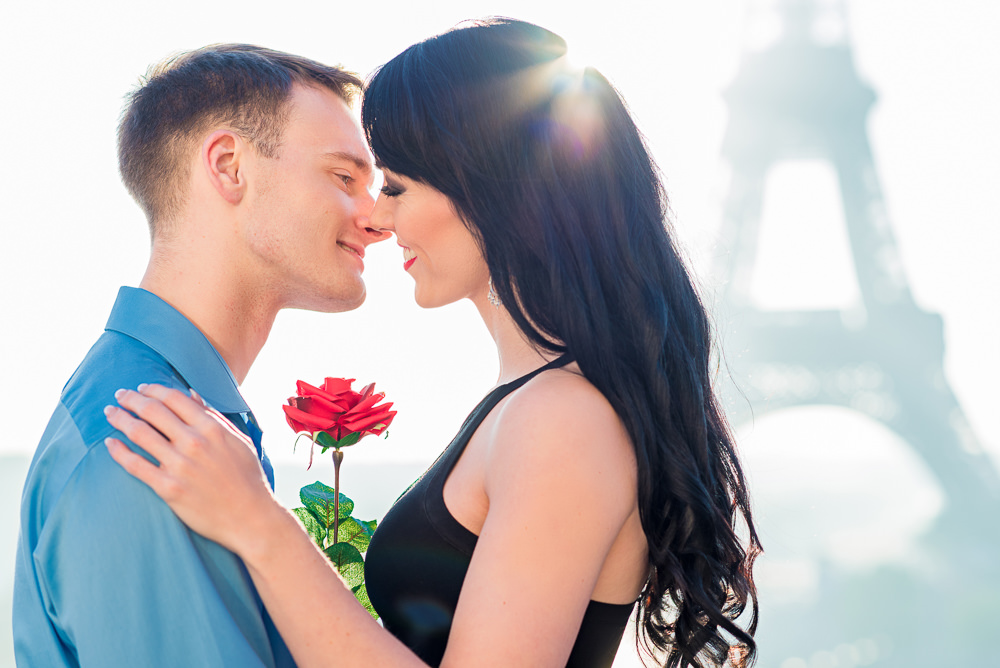 Couple holding red rose connecting in front of the camera of a professional photographer